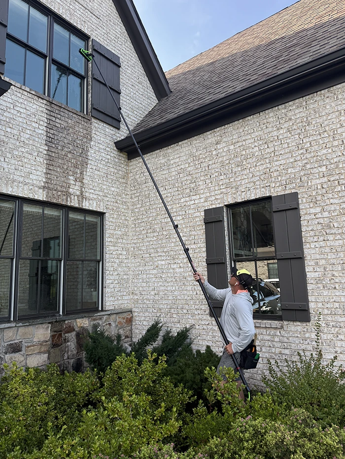 Landon cleaning an upstairs window with a water-fed pole